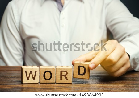 Man puts a wooden blocks with the inscription Word. The structural unit of language. Morphology. Word formation. Study of grammar. Linguistics