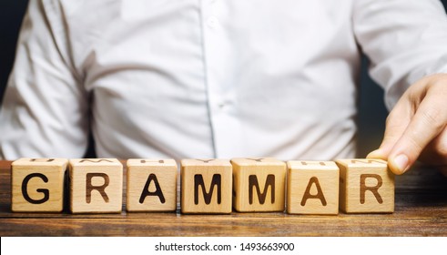 A man puts wooden blocks with the word Grammar. Set of structural rules governing the composition of clauses, phrases and words in a natural language. Phonology, morphology, syntax, phonetics