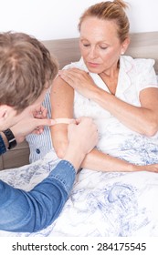 Man Putting Adhesive Bandage On Arm Of Woman