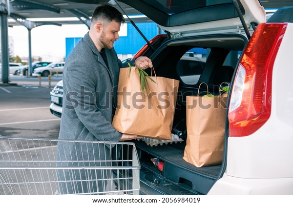 man\
putting bags with product in car trunk copy\
space