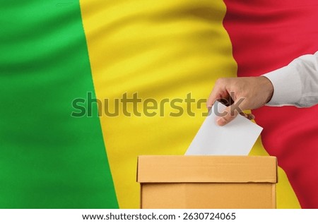 Man putting ballot into voting box on Mali flag background