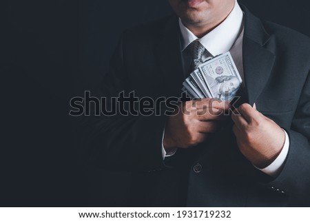 Man putting bribe money into pocket on black background, Concept for corruption, finance profit, bail and crime