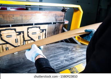 Man Putting Carton Into A Punching Machine. Cardboard Boxes Production. Paper Die Cutting Machine. 