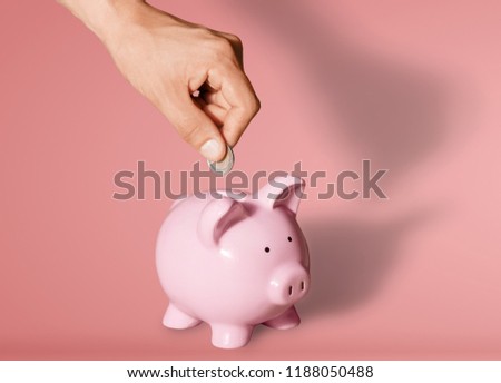 Man putting coin in pig moneybox