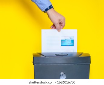 A Man Putting Confidential Documents Into A Paper Shredder