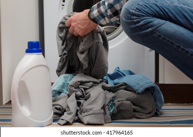 Man Putting Dirty Clothes Into Opened Washing Machine