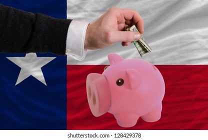 Man Putting Dollar Into Piggy Rich Bank Flag Of Us State Of Texas In Foreign Currency Because Of Inflation