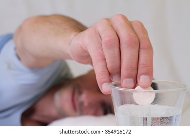 Man Putting Effervescent Medicine Into Glass Of Water. Selective Focus On Hand. Man Dropping Pill Into Glass Of Water. Healthcare And Medical Concept