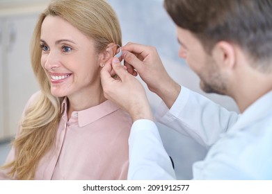 Man Putting Hearing Aid On Womans Ear