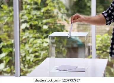 Man putting his vote into ballot box at polling station, closeup. Space for text