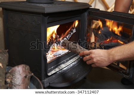 Man Putting Log Onto Wood Burning Stove