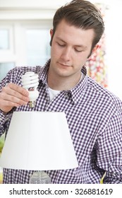 Man Putting Low Energy Lightbulb Into Lamp At Home