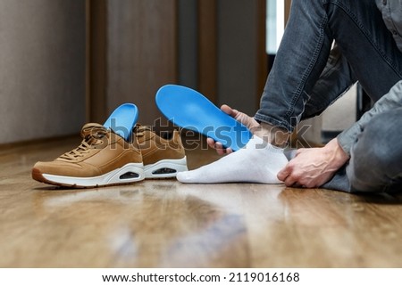 Man putting new custom insole in a shoe. Feet recreation medicine concept