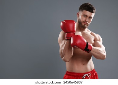 Man putting on boxing gloves against grey background. Space for text - Powered by Shutterstock