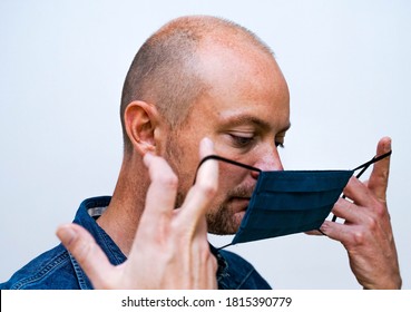 Man Putting On A Cloth Face Mask For Virus Protection, White Background.