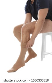 Man Putting On Compression Stocking Against White Background, Closeup