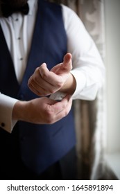 Man Putting On Cuff Links With Navy Vest