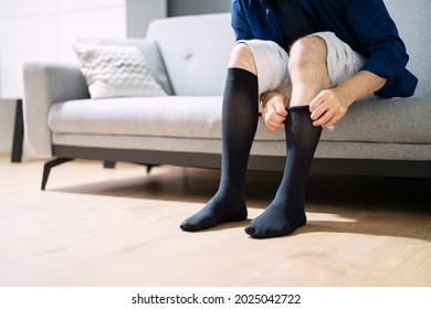 Man Putting On Medical Compression Stockings On Legs