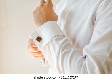 Man putting on a white shirt and cufflinks. Preparation. Formal wear.