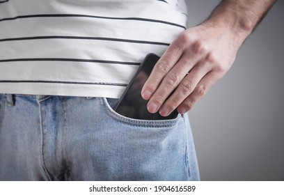 Man putting smartphone in pocket of jeans.