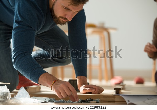 Man\
Putting Together Self Assembly Furniture In New\
Home
