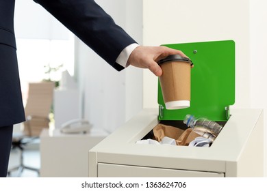 Man Putting Used Paper Cup Into Trash Bin In Office, Closeup. Waste Recycling