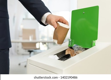 Man Putting Used Paper Cup Into Trash Bin In Office, Closeup. Waste Recycling