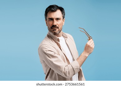 Man with a questioning expression holding spectacles, showing bewilderment and doubt