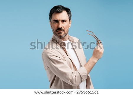Man with a questioning expression holding spectacles, showing bewilderment and doubt