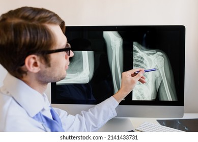 Man radiologist analyzing a patient arm and forearm bones x ray with a humerus fracture.