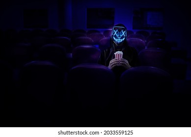 Man in a raincoat and a glowing mask with popcorn. tinting. selective focus