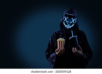 Man in a raincoat and a glowing mask with popcorn. tinting. selective focus