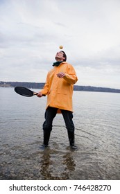 man in raincoat with racket and ball