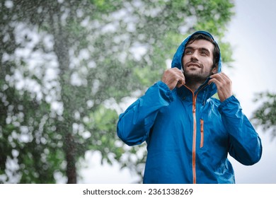 man in a raincoat in the rain in a rainy day in the park, the concept of the rainy season - Powered by Shutterstock