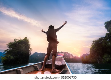 Man Raised Hands Enjoying To Adventure Trip Of A Lifetime Floating In A Boat On The Asia Lake With Sunset Among The Islands With Mountains 