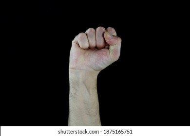 A Man Raised His Fist High. Raised Fist Gesture For Support Or Solidarity, Struggle, Opposition, Male Hand On Isolated Black Background