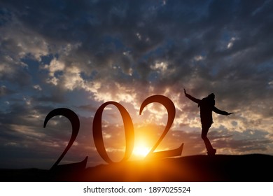 Der Mensch erhebt sich auf dem Sonnenuntergangshimmel oben auf dem Berg und die Zahl wie 2021. Frohes neues Jahr und Urlaubskonzept.