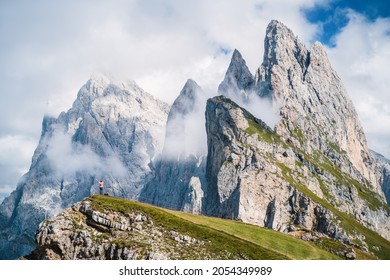 A man raising his hands in front of epic Furchetta and Sass Rigais peaks in Seceda, Dolomites Alps, Odle mountain range, South Tyrol, Italy, Europe. Travel vacation concept