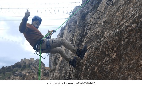 
man rappelling down the mountain