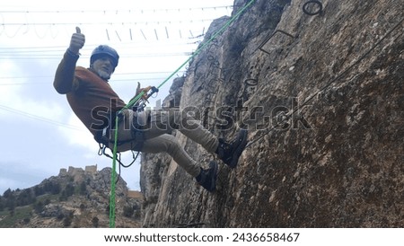 
man rappelling down the mountain