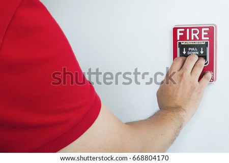 Man is reaching his hand to push fire alarm hand station