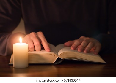 Man Reading Book With Candle Light