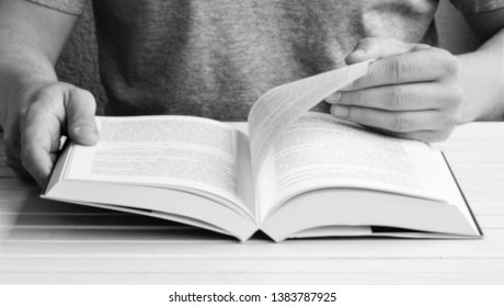 Man is reading a book, close up, vintage black and white style. Hand open book for reading. Man is flipping the pages of a book. Close-up picture of hands and book. Out of focus, intentionally blurred
