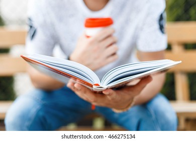 Man reading a book and drinking coffee.Young man resting and drinking coffee.