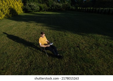 Man Reading A Book In Garden Recliner Chair. Summer Vacation In The Yard Garden. Scandinavian Male Life In Holidays. Good Living. View From The Top. Beautiful Young Man Resting. Daily Simple Life