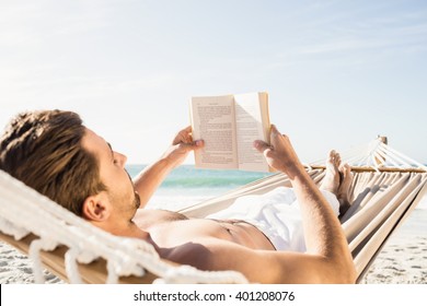 Man Reading Book In Hammock On The Beach