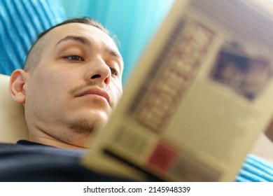 A Man Is Reading A Book Lying On The Couch At Home, Soft Focus. Home Living Room Lounge. Selective Focus