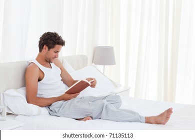 Man Reading A Book On His Bed At Home