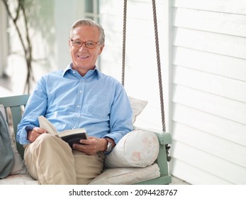 Man Reading Book On Porch Swing