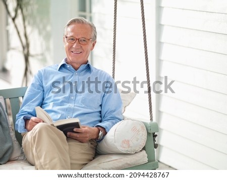 Man reading book on porch swing